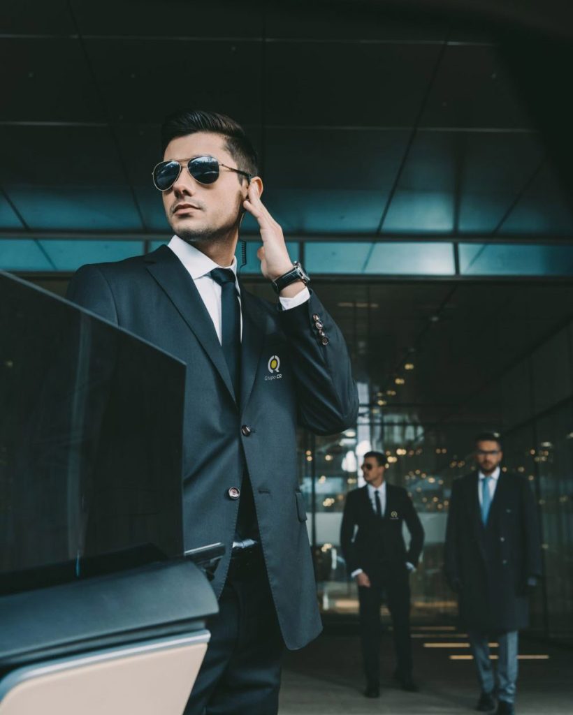 bodyguard-opening-car-door-for-businessman-and-listening-security-earpiece-e1631421593194-pczngmdv2v6fg4jhw9ff6gip9kmprsxvbxexbulrys